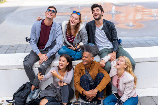 istock group of young students looking at smartphone and have fun,  protective mask for prevention of coronavirus pandemic on their arms, multiethnic friends at college,  new normal concept of social hangout 1337847167