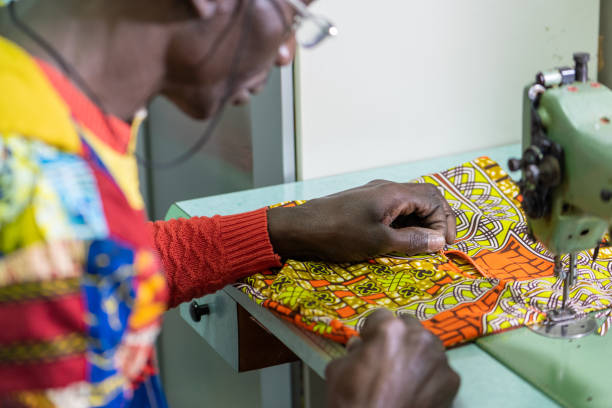 istock african tailor dressed in traditional clothes and fabrics at work in his workshop, production of unique clothes with modern style and colors of africa, small business, business concept of craftsman 1337847254