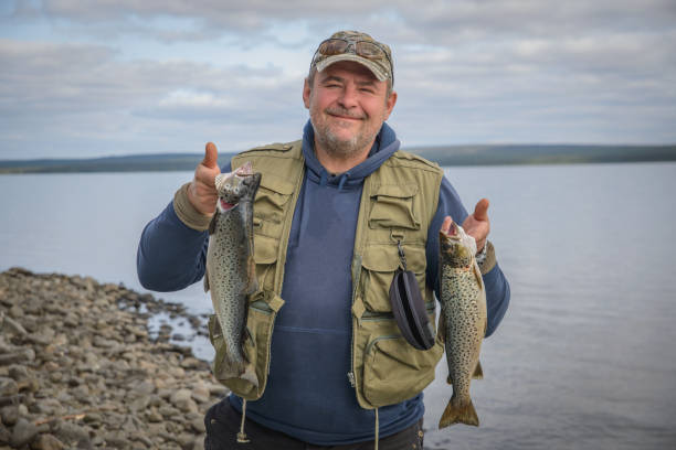 un hombre con una trucha capturada. - fisherwoman fotografías e imágenes de stock