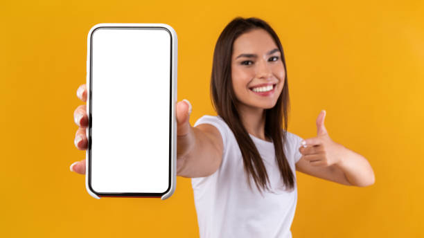 istock Woman showing white empty smartphone screen and thumbs up 1337850566