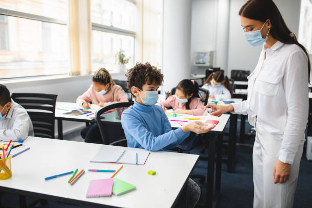istock Teacher applying antibacterial sanitizer on pupil's hands 1337850699