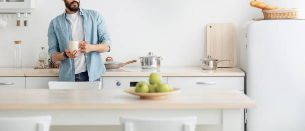 istock Home relax. Young unrecognizable man drinking morning coffee in kitchen and dreaming, panorama with empty space 1337856200