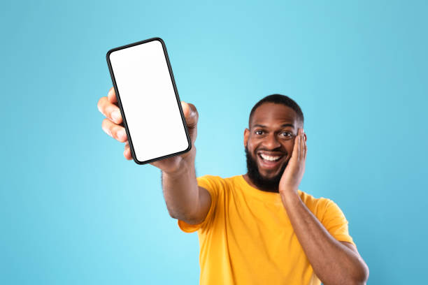 istock Excited black man presenting smartphone with empty screen, recommending website or ad, blue background, space for mockup 1337856245