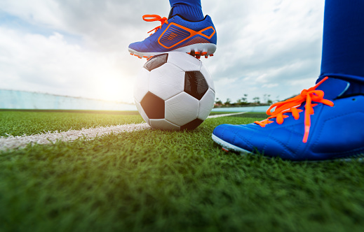 Little boy playing soccer ball on sports field.