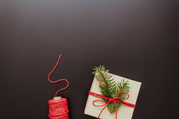 un paquet cadeau avec un arc rouge et une ficelle sur fond sombre - wrapped package string box photos et images de collection