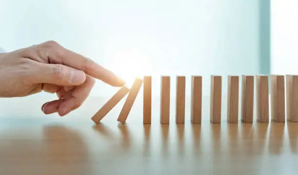 Man finger pushing domino pieces.