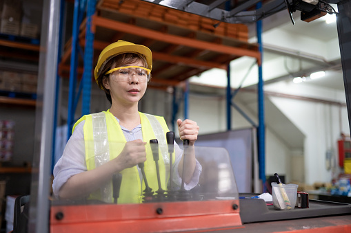Asian Chinese warehouse female worker operating forklift working in industry factory