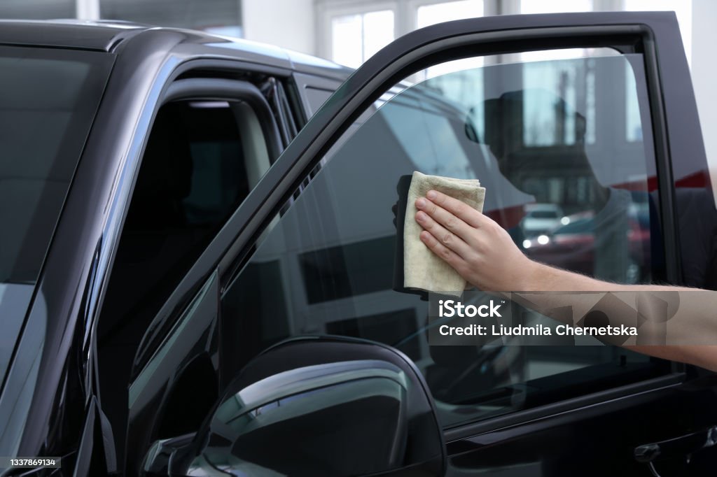 Worker tinting car window with foil in workshop, closeup Car Stock Photo