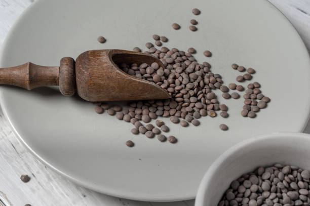istock Wooden measuring spoon with raw lentils. 1337870981