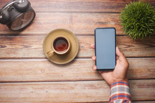 istock young man hand using smart phone with tea and cookies on table 1337877014