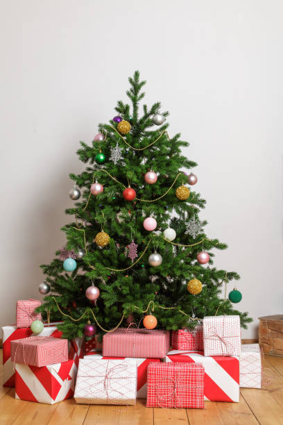 istock Wrapped boxes with gifts under a Christmas tree in a light room. 1337877300