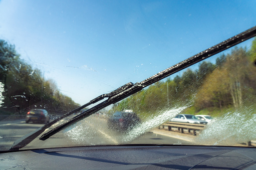 Using a squirt of cleaning fluid and the windscreen wipers to clear the windscreen for improved visibility during a motorway journey.