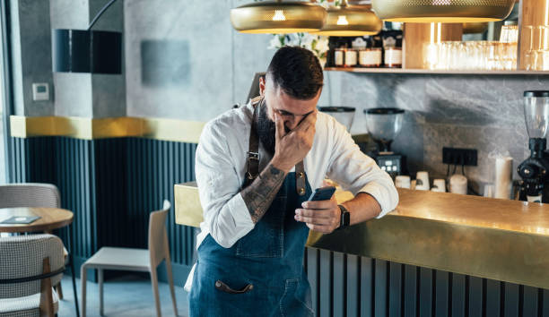 istock Happy Barista Using Mobile Phone in a Cafe 1337879023