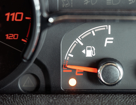 A low fuel indicator light below the fuel gauge on a car, showing that the fuel is almost empty.
