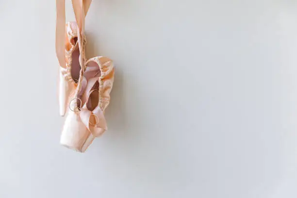 New pastel beige ballet shoes with satin ribbon isolated on white background. Ballerina classical pointe shoes for dance training. Ballet school concept. Copy space