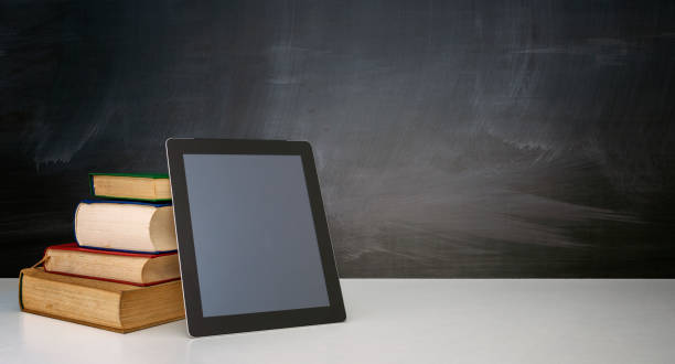 istock Books and tablet on the desktop on blackboard background 1337880879