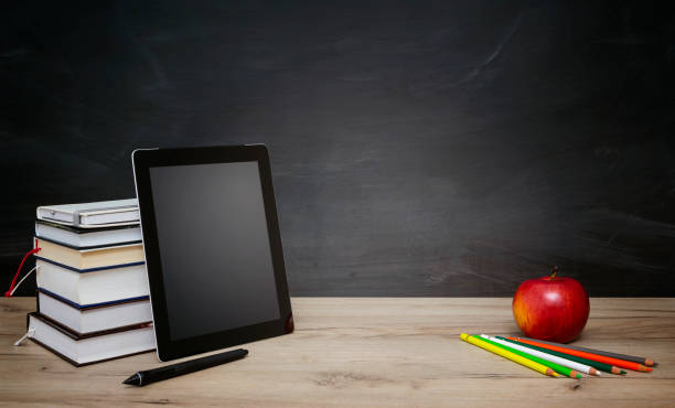 istock Books and tablet on the desktop on blackboard background 1337881101