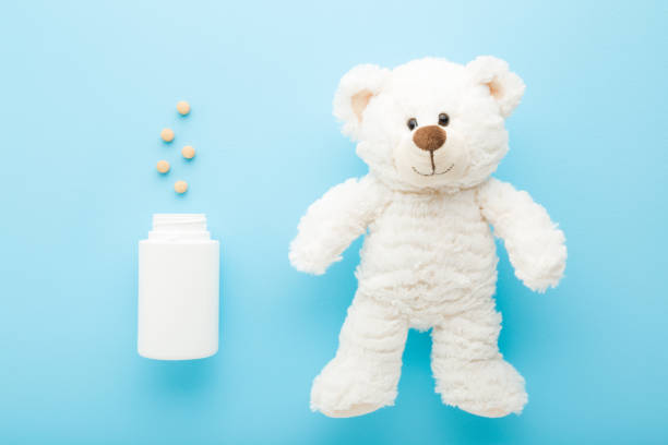 istock White teddy bear and plastic bottle with pills on light blue table background. Pastel color. Closeup. Vitamins for children. Medical, pharmacy and healthcare concept. Top down view. 1337881202