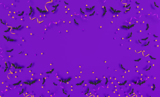 Black bats and orange party streamers sitting over purple background. Horizontal composition with copy space. Halloween concept.