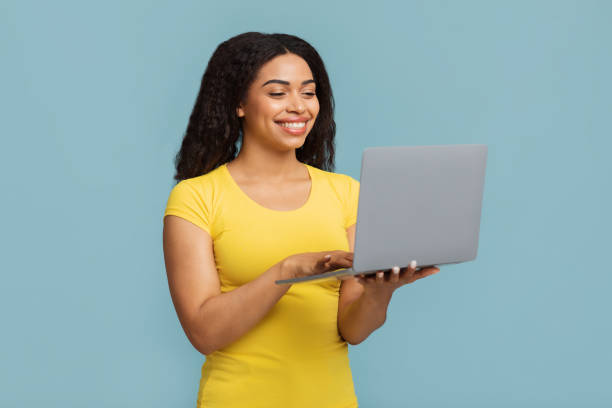 istock Online education programs. Happy black woman holding and using newest laptop computer over blue background 1337890110