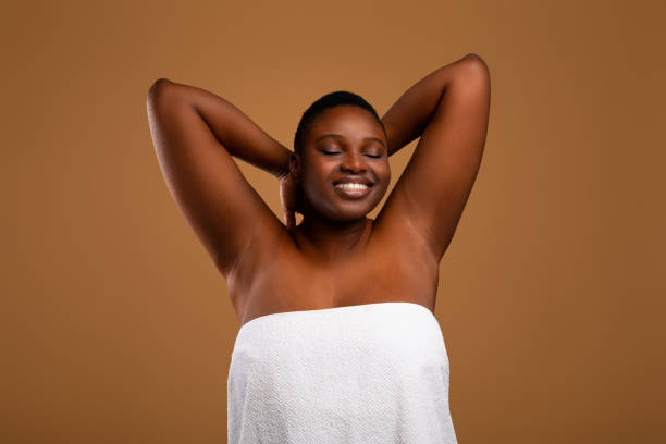 Portrait of beautiful plus size African american woman showing armpits Portrait Of Happy Chubby Black Female Posing With Hands Up, Showing Her Smooth Armpits, Cheerful African American Lady With Beautiful Skin Posing In White Towel Over Brown Studio Wall, Copy Space artists model photos stock pictures, royalty-free photos & images