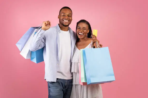 Photo of Portrait of happy afro couple holding credit card and bags