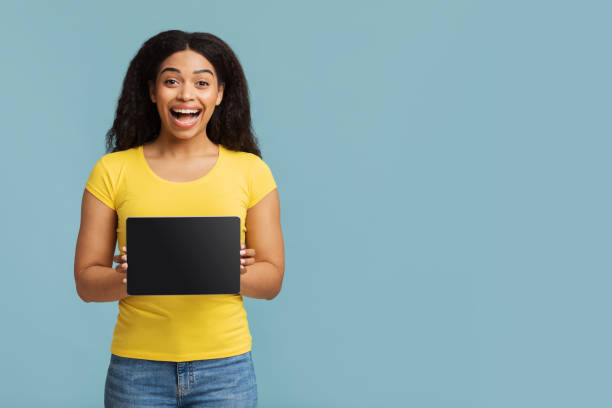istock Overjoyed african american lady showing digitral tablet with black screen, demonstrating space for mockup design 1337892959