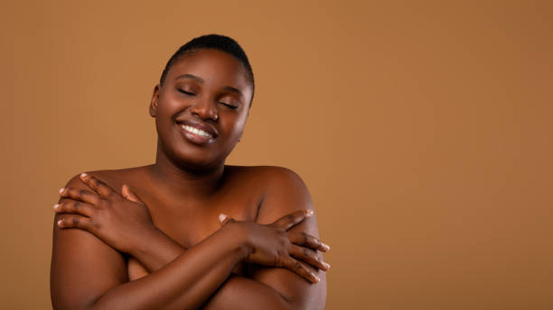 자신을 껴안고 있는 아름다운 플러스 사이즈 흑인 여성의 초상화 - body women naked beauty 뉴스 사진 이미지