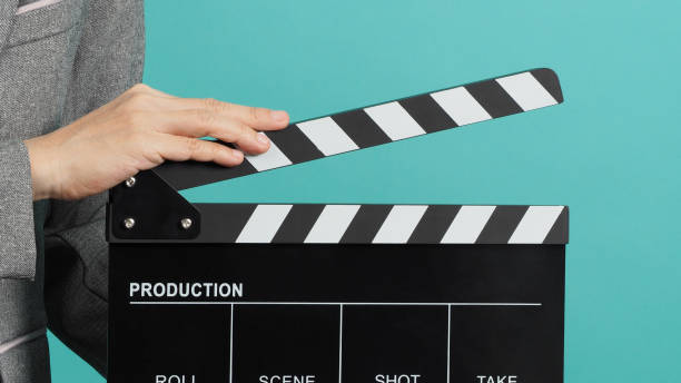 istock Black Clapperboard or movie Clapper board for videography with hands in grey suit on mint green Tiffany Blue background. 1337893367