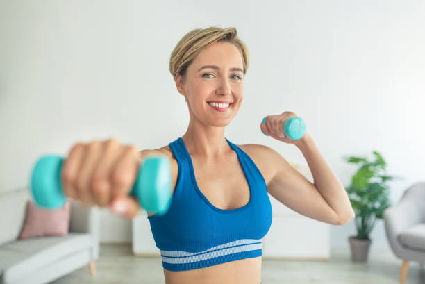 istock Smiling Middle-Aged Woman Exercising With Two Dumbbells At Home 1337894708