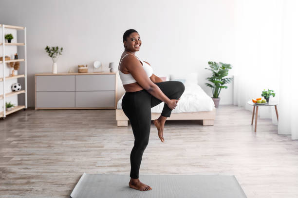 istock Overweight black lady stretching leg, making flexibility exercises on yoga mat, leading active lifestyle during covid 1337895161