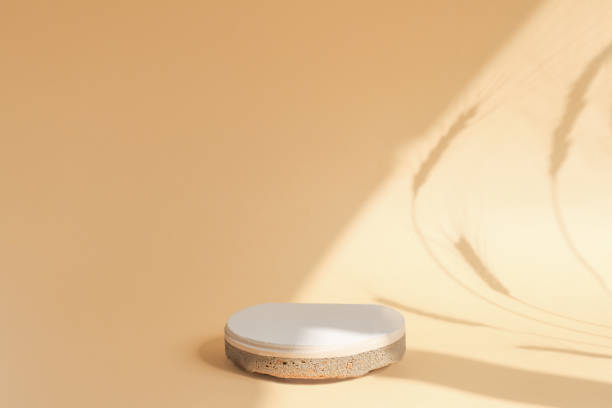 istock A round stone stage on a beige background with a central position in the composition. Empty showcase for cosmetic products. Abstract shadows with plant spikelets and sunbeams. 1337899219