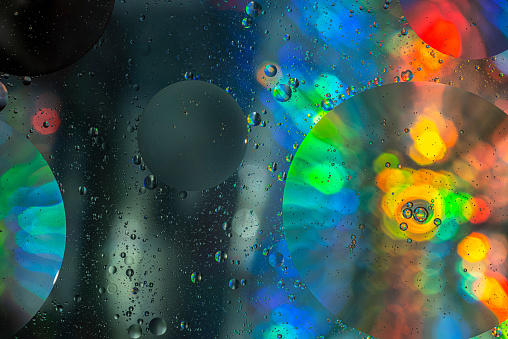 Close up image of mixed oil with water on colorful gradient background