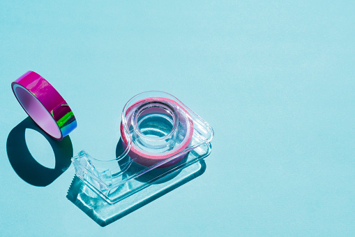 Adhesive tape dispenser on colored background