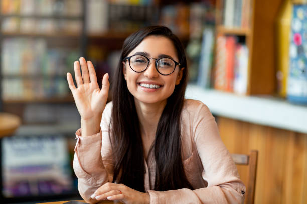 Video call. Happy young arab lady greeting someone, having virtual conference, waving with hand to camera and smiling