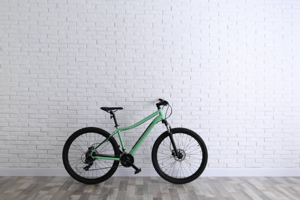 istock Modern green bicycle near white brick wall. Space for text 1337905418