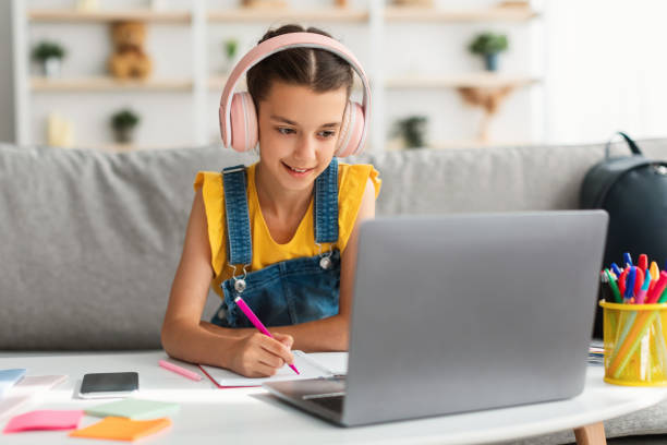 istock Girl sitting at desk, using laptop, drawing in copybook 1337906226