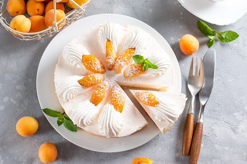 Fresh apricot cheesecake on light background. Top view. Healthy summer dessert concept. Selective focus.