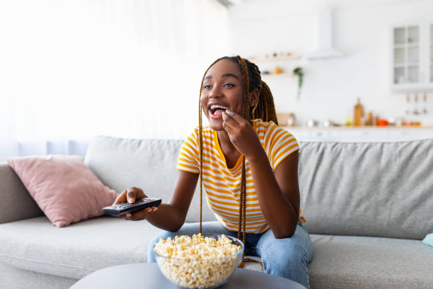 Joyful african american lady watching TV at home