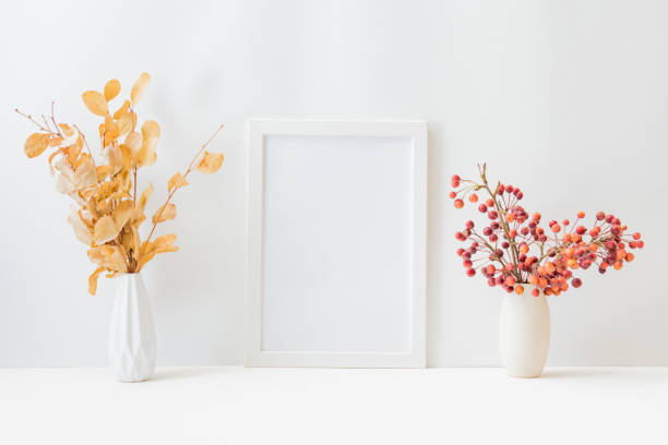 istock Home interior with decor elements. Mockup with a white frame, Dry autumn leaves in a vase on a light background 1337907326