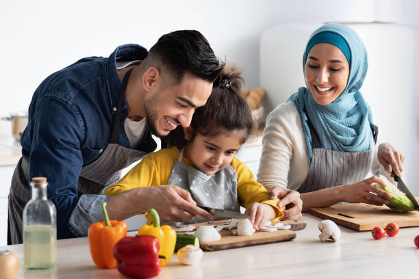 un jeune père arabe montre comment couper des champignons à sa petite fille - middle eastern ethnicity photos et images de collection