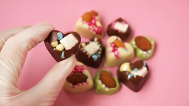 istock Pastry chef's hand in gloves holds a heart-shaped candy. Sweets on pink 1337909976