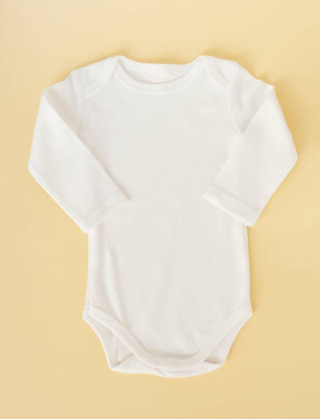 istock White baby clothes on a yellow background, flat lay. Mockup for design 1337911097