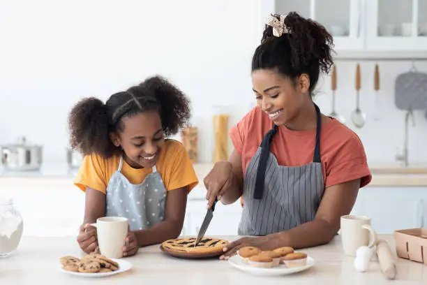 Photo of Excited black mom and daughter tasting homemade pie