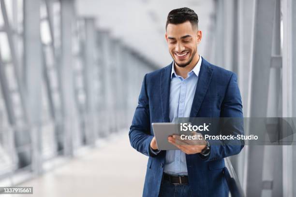 Happy Arab Businessman Booking Hotel Online While Using Digital Tablet In Airport Stock Photo - Download Image Now