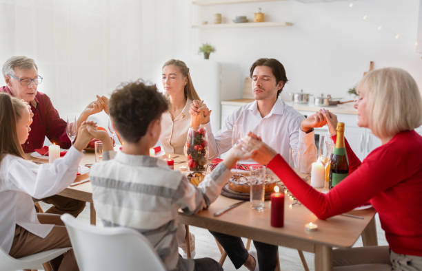 istock Big multi generation family holding hands and praying before festive dinner at home 1337916385