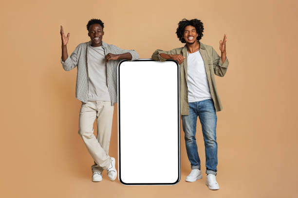 istock Two Excited Black Guys Leaning At Big Smartphone With Blank White Screen 1337918919