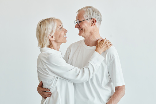 Romantic and cheerful Asian well-being senior couple enjoy dancing and holding hands to music together with smiles and happiness in the living room. Senior retirement activity at home.