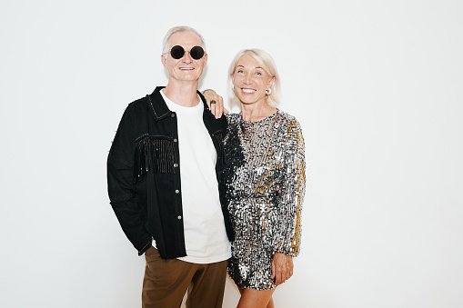 Waist up portrait of glamorous senior couple posing against white background at party, shot with flash