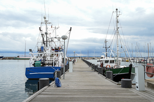 Fishing boats at the wooden dock in the port of Sassnitz on the island of Rugen in the Baltic Sea against a cloudy sky, travel and tourist destination, copy space, selected focus